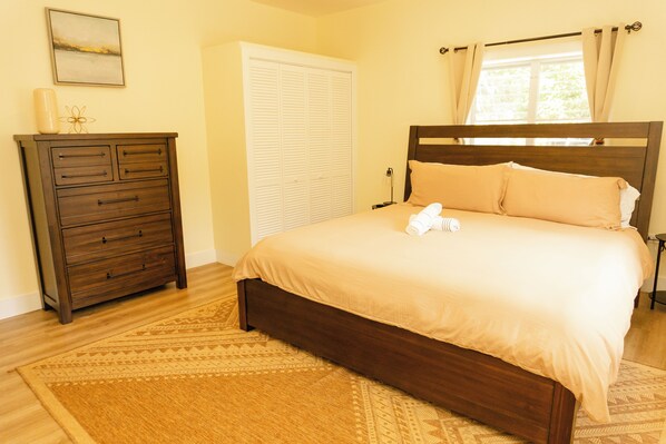 A bedroom with a bed, a dresser, a closet, and a window with curtains.