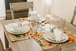 A neatly set dining table with plates, bowls, glasses, and cutlery.