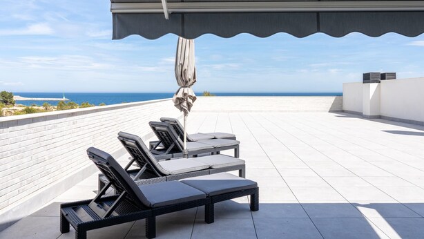 A rooftop terrace with lounge chairs and a covered area, overlooking a coastal landscape. - Dream vacations in front of the Mediterranean Sea (L'Ametlla de Mar)