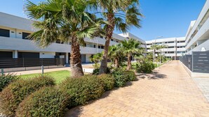 A modern building with a paved walkway, palm trees, and neatly trimmed bushes. - Dream vacations in front of the Mediterranean Sea (L'Ametlla de Mar)
