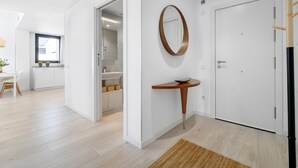 A modern, well-lit hallway with a wooden floor, a white door, and a mirror on the wall. - Dream vacations in front of the Mediterranean Sea (L'Ametlla de Mar)
