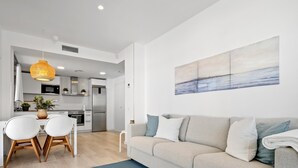 A modern living room with a grey sofa, a blue rug, and a dining area with white chairs and a table. - Dream vacations in front of the Mediterranean Sea (L'Ametlla de Mar)