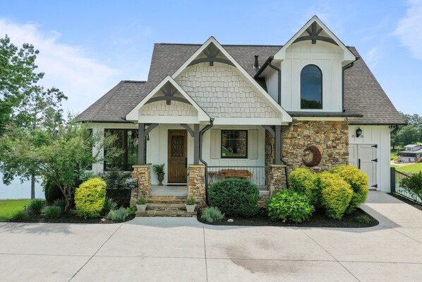 A two-story house with a stone facade, a gabled roof, and a front porch with steps.