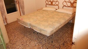 Een kamer met een bed, een deur voorzien van gordijnen en een wandlamp.