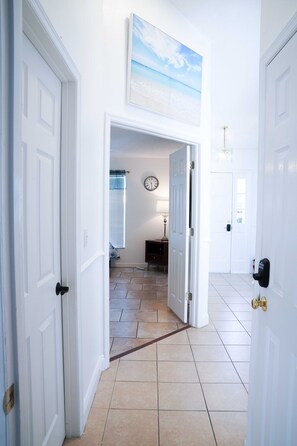 Stylish hallway leads to a cozy bedroom with a window and comfortable seating area.