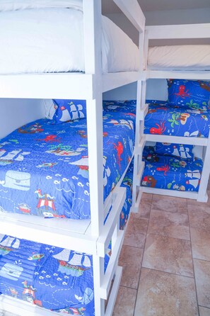 Cozy nautical-themed bunk beds feature white frames and blue bedding with sea creatures and ships.