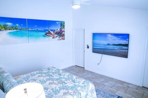 Enjoy a scenic beach view on the large flat-screen TV, complemented by a vibrant coastal theme and a comfortable bed.