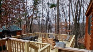 Terraza de madera con mesa y sillas, rodeada de árboles.