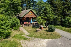 Un chalet rustique doté d’un porche, entouré d’une forêt dense.