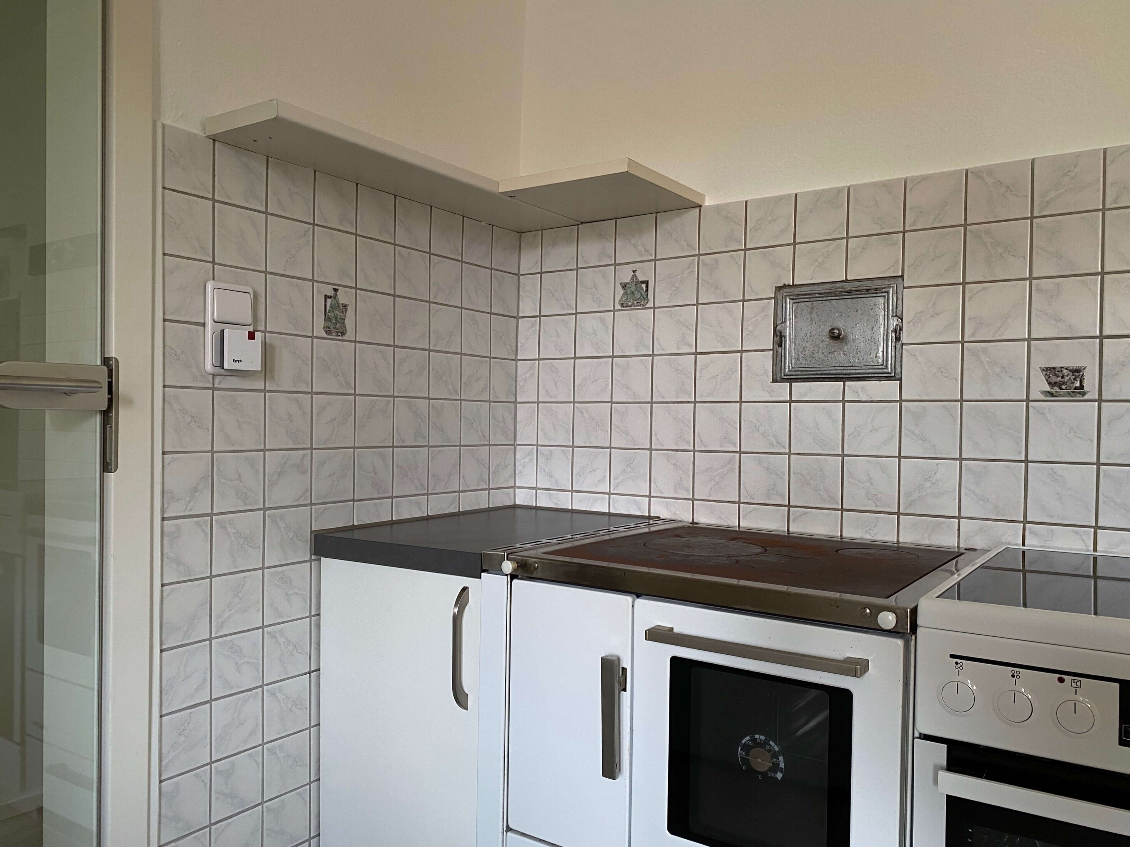 Een keuken met witte kastjes, een fornuis en een magnetron.