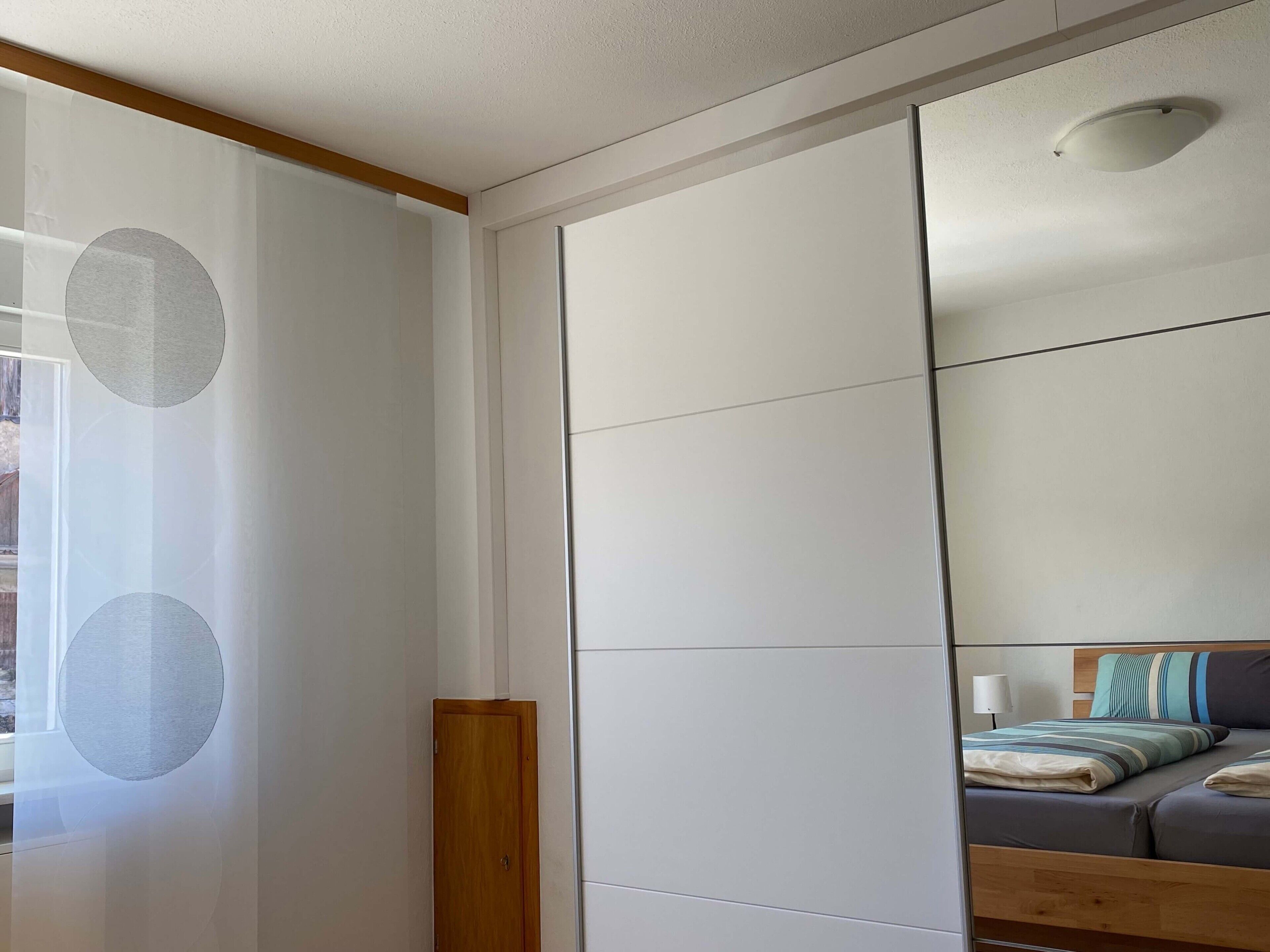 Quarto com cama, cabeceira de madeira, mesa de cabeceira e espelho na parede.