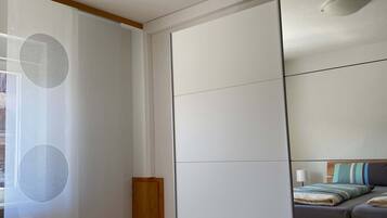 Quarto com cama, cabeceira de madeira, mesa de cabeceira e espelho na parede.