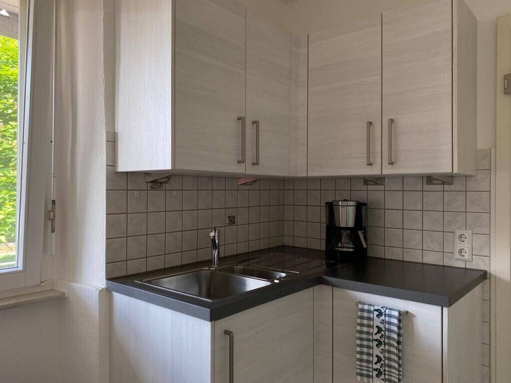 A kitchen with white cabinets, a black countertop, and a coffee maker.