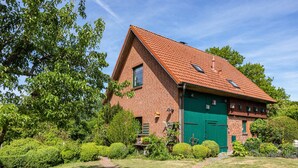 A brick house with a green door, surrounded by a well-maintained garden with hedges and a pathway. - Holiday Home 'Forsthof Schulte' with Private Terrace, Private Garden and Wi-Fi (Pronstorf)