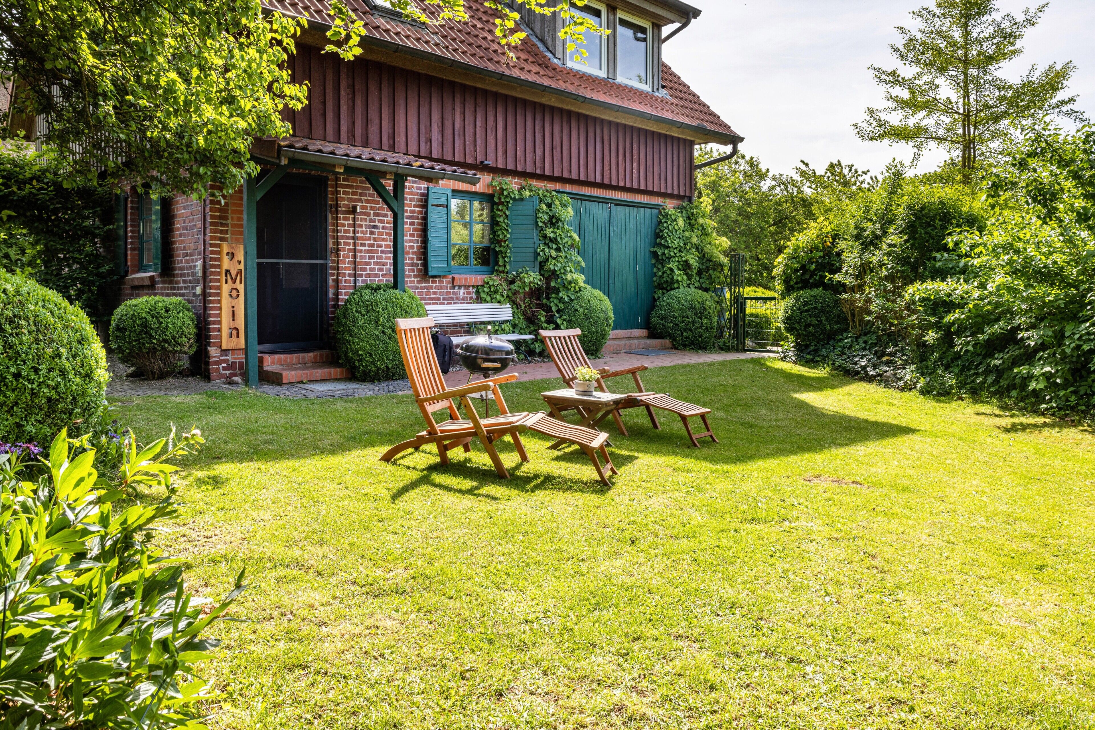 A house with a brick exterior, a covered porch, and a well-maintained lawn with outdoor furniture.