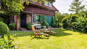 A house with a brick exterior, a covered porch, and a well-maintained lawn with outdoor furniture. - Holiday Home 'Forsthof Schulte' with Private Terrace, Private Garden and Wi-Fi (Pronstorf)