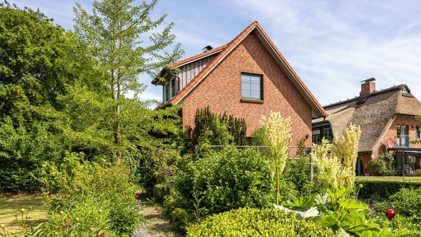 A brick house with a garden, a visible window, and a thatched roof. - Holiday Home 'Forsthof Schulte' with Private Terrace, Private Garden and Wi-Fi (Pronstorf)