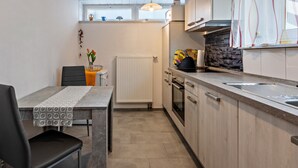Une cuisine moderne avec un coin repas, un four encastré et une fenêtre au-dessus du plan de travail.
