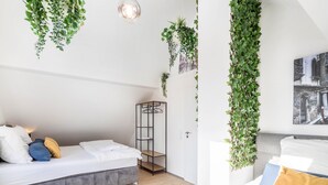 Ein Schlafzimmer mit Bett, hängenden Pflanzen, einem Kleiderschrank und einer Pendelleuchte.
