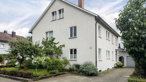 Um edifício de dois andares com fachada simétrica, várias janelas e uma entrada com calçada.