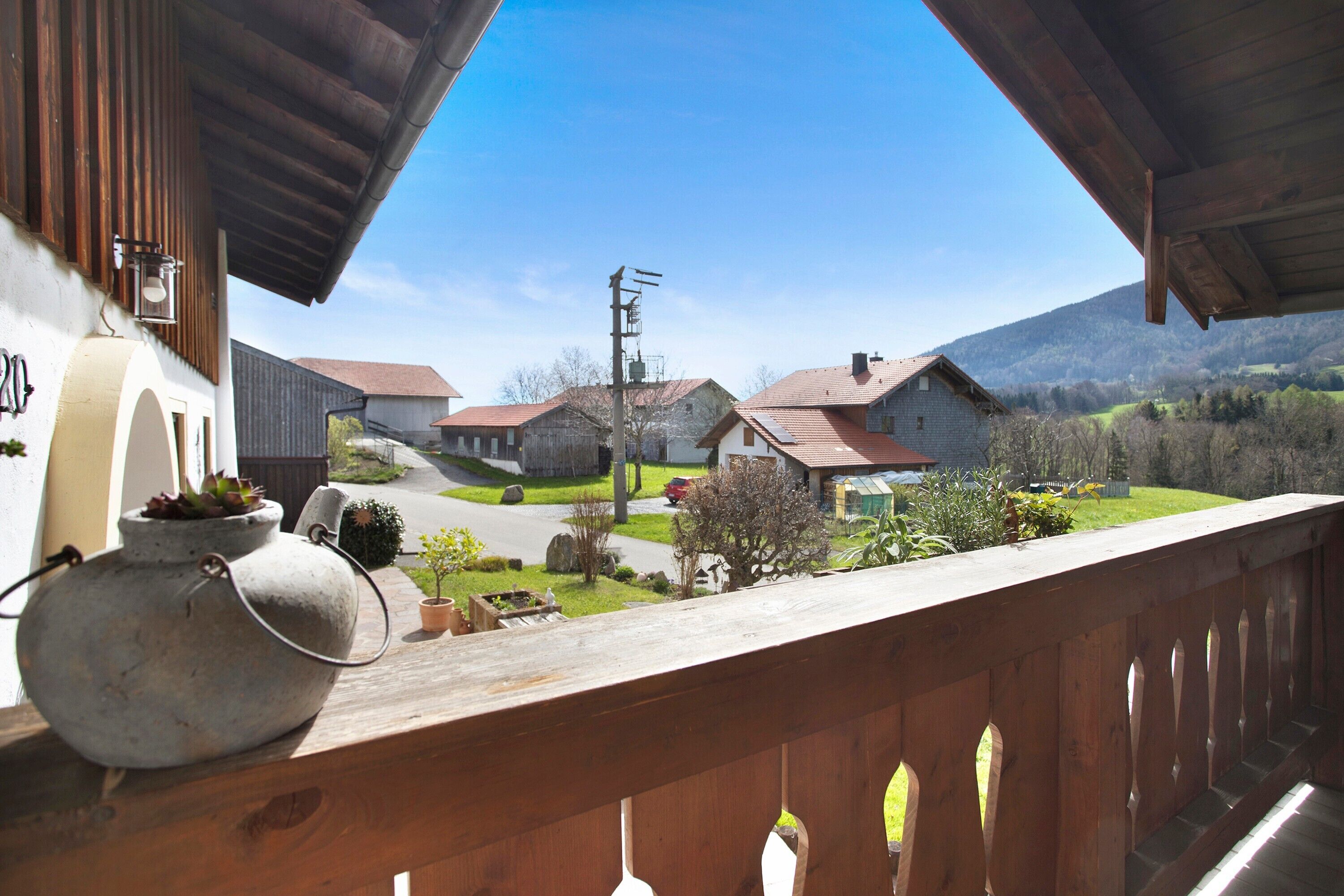A balcony with a view of a village, a rustic building, and a mountain in the background.