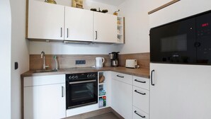 A compact kitchen with white cabinetry, a built-in oven, a microwave, and a coffee maker. - Studio Apartment 'Lackner' with Mountain View, Balcony and Wi-Fi (Teisendorf)