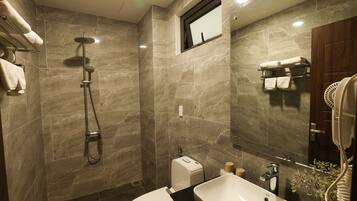 A modern bathroom with a shower, toilet, sink, and hairdryer.