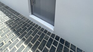 Una porta grigia con una piccola finestra, una maniglia in metallo e una zoccola bianca.