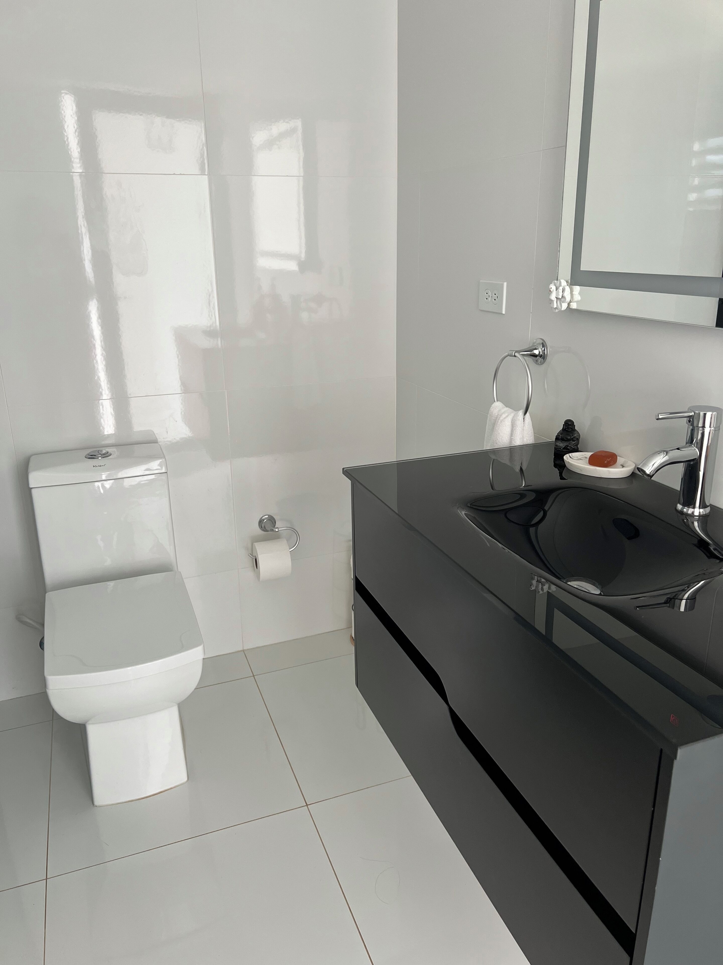 Un baño moderno con inodoro, lavabo y espejo.