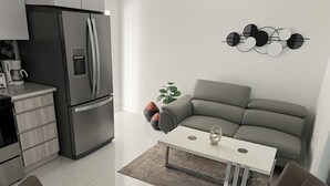 Una cucina moderna con frigorifero integrato, un tavolo da pranzo con sedie e un divano grigio.