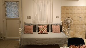 Un lit avec des coussins à motifs, une fenêtre avec un rideau, un climatiseur et un mur recouvert de carreaux.