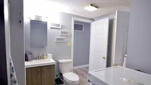 A bathroom with a toilet, sink, and cabinet.