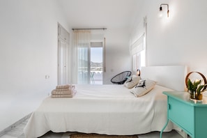 Een slaapkamer met een bed, nachtkastje, stoel en uitzicht.