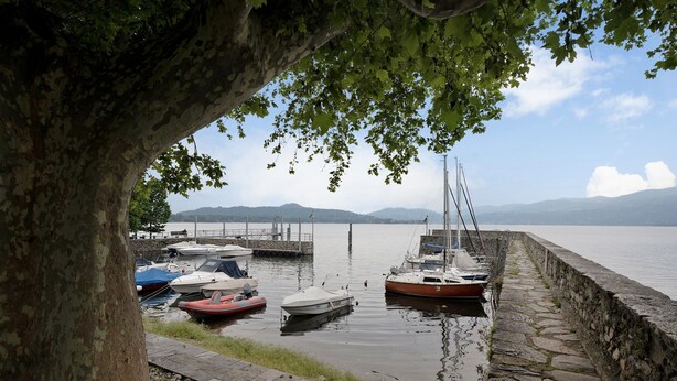 A calm marina with boats docked, a stone wall, and a tree in the foreground. - Holiday Home 'Casa Romantica' with Private Terrace, Balcony and Wi-Fi (Ispra VA)