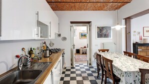 A kitchen with a checkered floor, a sink, and a dining area with a table and chairs. - Holiday Home 'Casa Romantica' with Private Terrace, Balcony and Wi-Fi (Ispra VA)