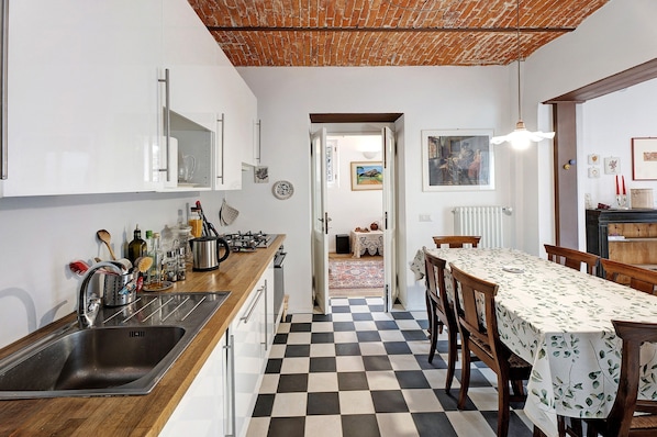 A kitchen with a checkered floor, a sink, and a dining area with a table and chairs.