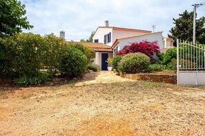 A house with a pathway leading to the entrance, surrounded by greenery and a gravel driveway. - Villa 'Chez Tao' with Pool, Garden, Terrace & Wi-Fi (Bandol)
