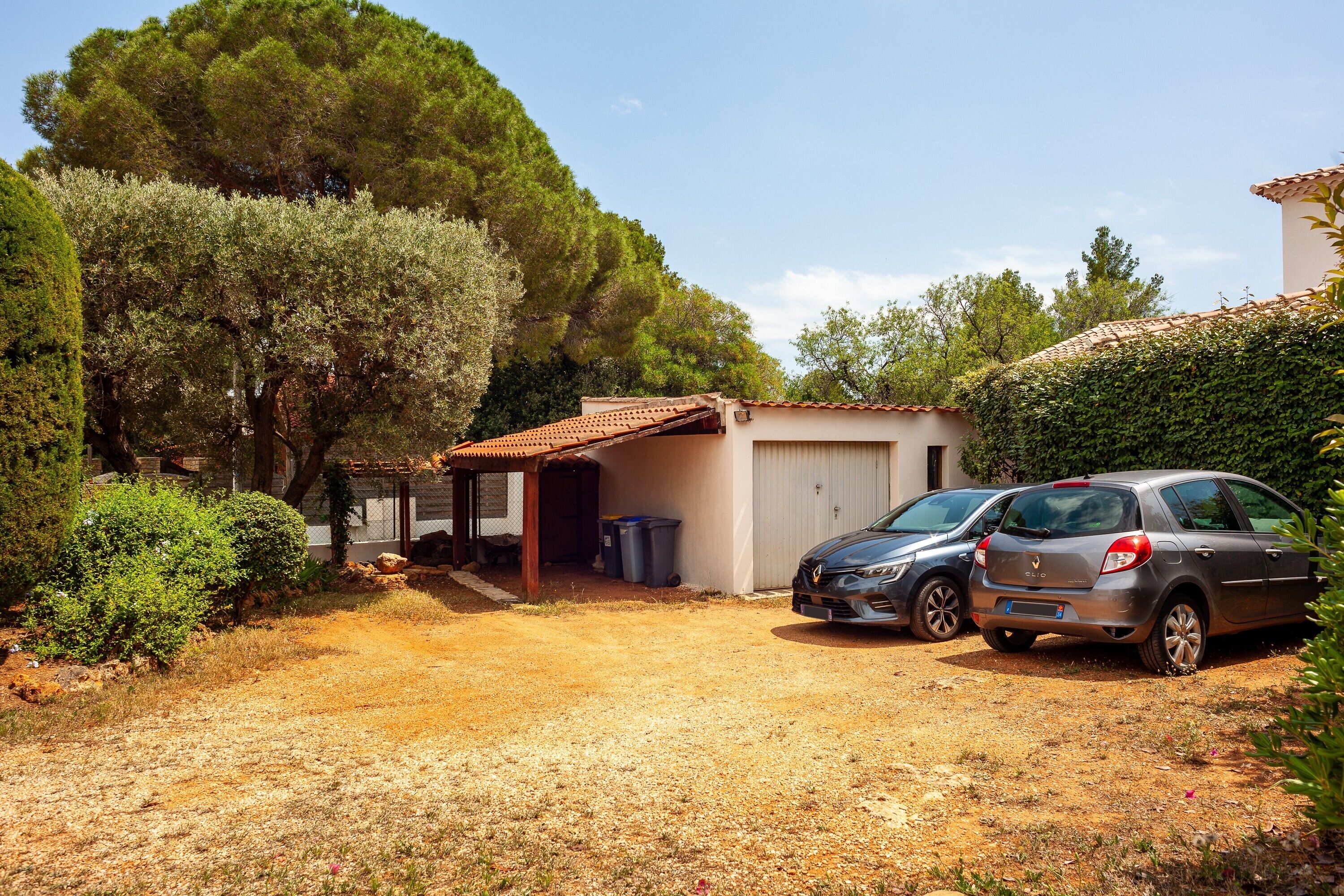 Imóvel residencial com garagem, carros estacionados e acesso por estrada de terra.