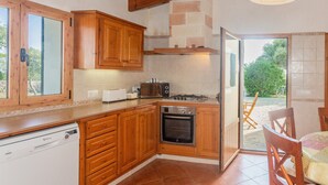 Cozinha com armários de madeira, máquina de lavar louça, fogão e vista para o exterior.