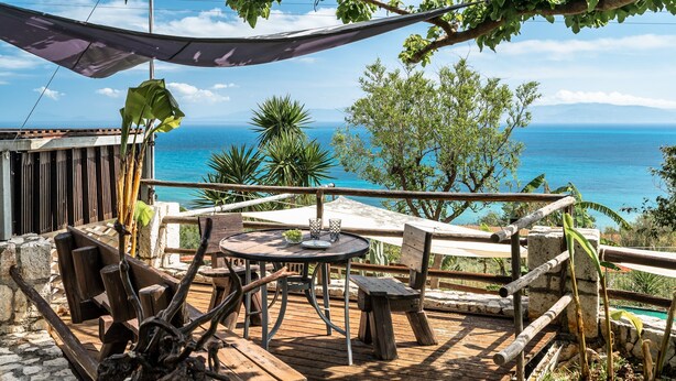 Une terrasse en bois avec une table et des chaises, donnant sur une étendue d’eau.