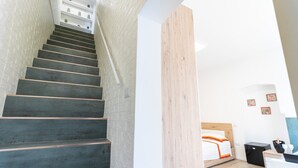 Una escalera que lleva a un dormitorio con una cama, un escritorio y una silla.