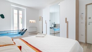 Una habitación de hotel moderna con cama, un baño pequeño y vistas al exterior.