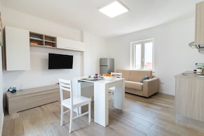 Une cuisine moderne avec des meubles blancs, une table à manger et un four encastré.