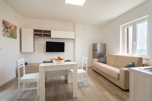 Un espace de vie moderne comprenant une table à manger, des chaises, un canapé, un téléviseur et un réfrigérateur.
