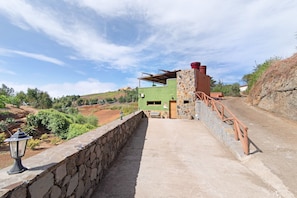 A building with a stone wall, a wooden staircase, and a view of the surrounding landscape.