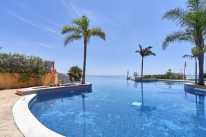 A clear blue infinity pool with palm trees, a lifeguard stand, and a view of the sea. - Holiday Home 'Casa Fuentes 2 B2' with Sea Views, Wi-Fi & Air Conditioning (Almuñecar)