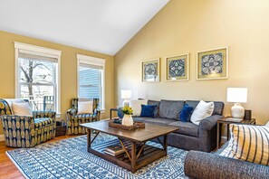 A living room with a sofa, two armchairs, a coffee table, and a patterned rug.