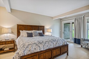 A bedroom with a large bed, two bedside tables, a chair, and a sliding glass door to the outside. - Condo with Fireplace & Golf Views, Fox Hollow (Quechee)