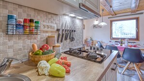 A kitchen with a tiled backsplash, a gas stove, and various kitchen utensils.