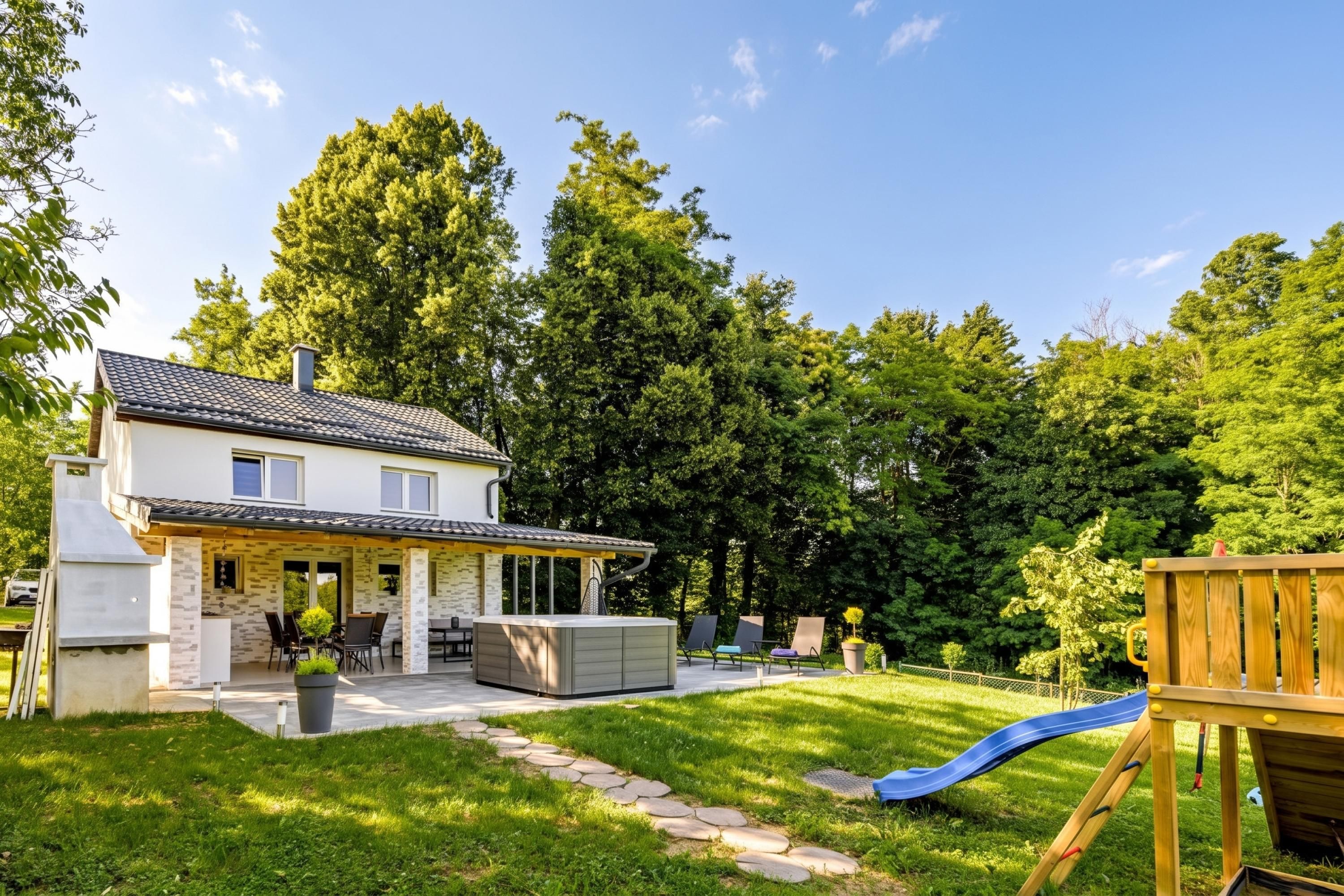 Une maison à deux étages dotée d’une terrasse, d’un espace salon extérieur et d’un toboggan.